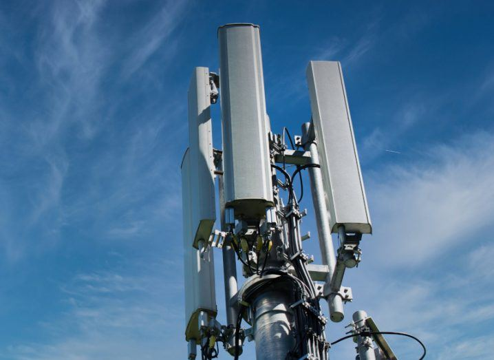 The image shows a close-up of a cellular tower with multiple antennas against a blue sky. The tower is part of a Distributed Antenna System (DAS).